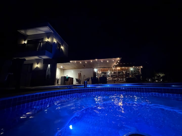 Casa iluminada refletida na piscina à noite